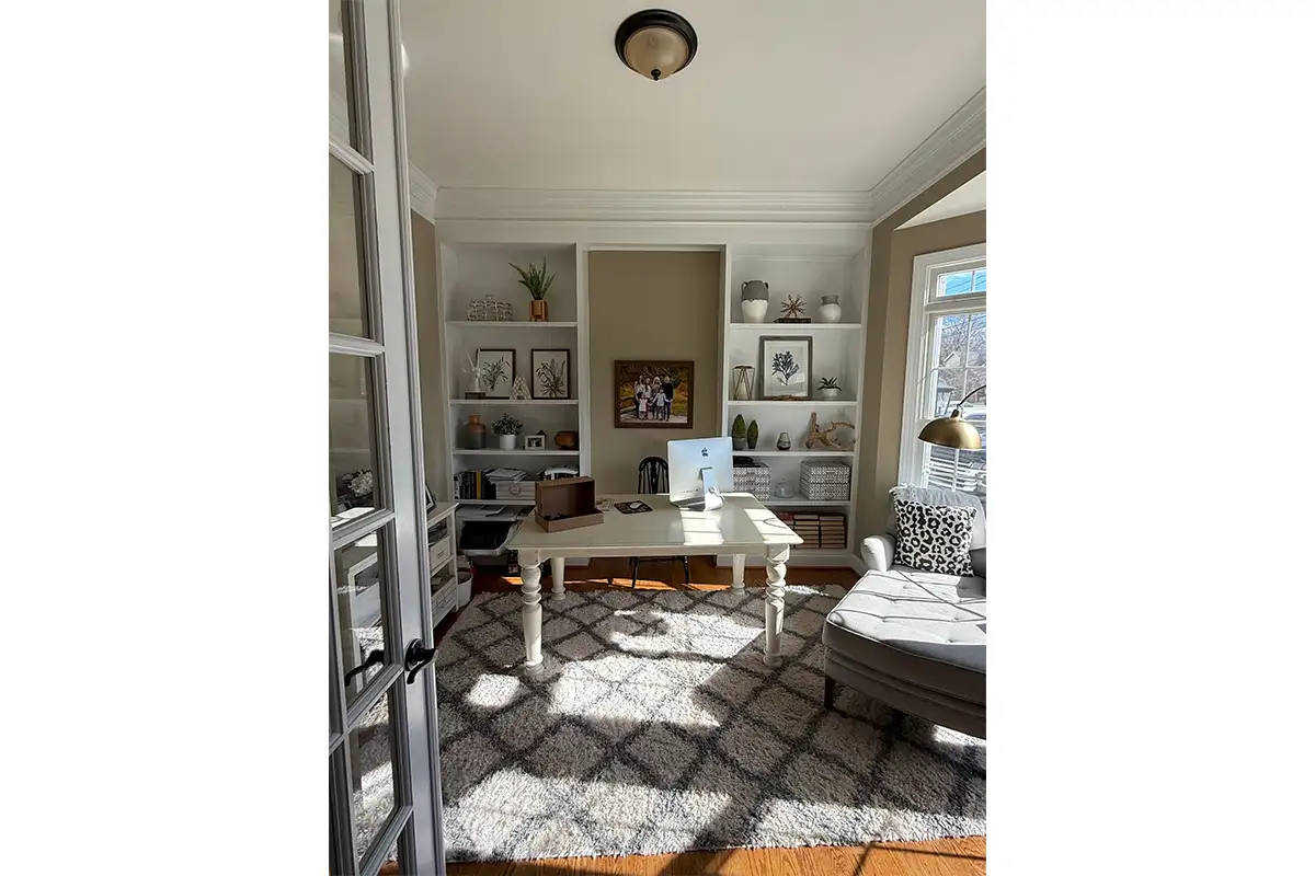White office space with patterned rug, white desk, and built-in shelves