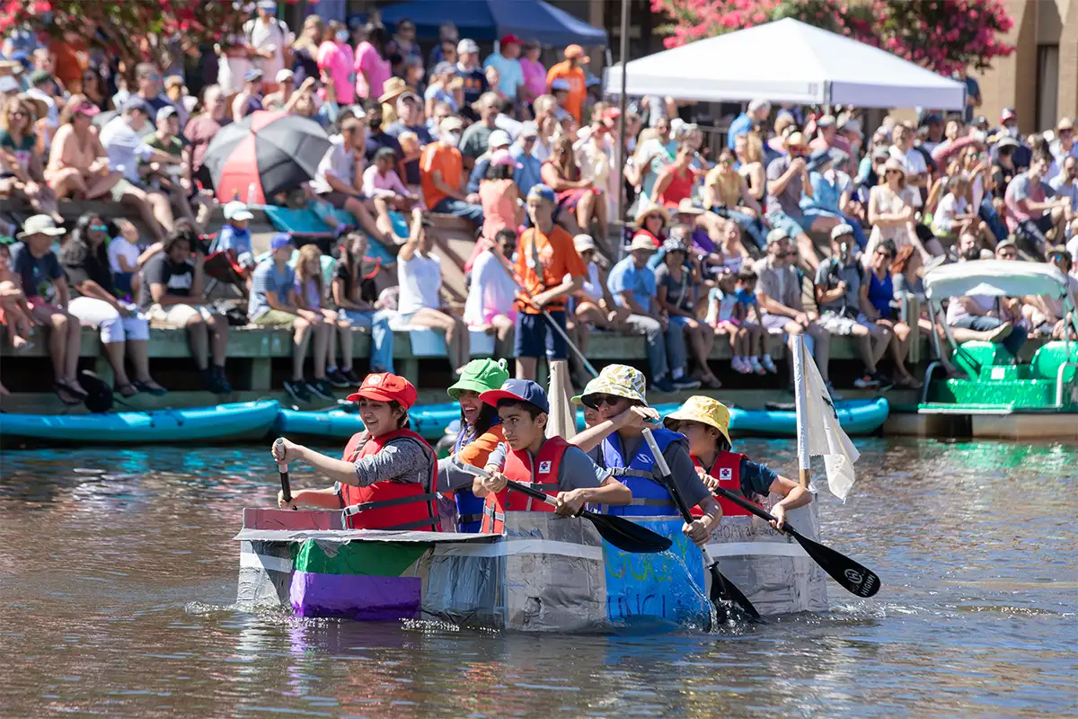 Crowd watching kids row in homemade cardboard boats on Lake Anne during regatta