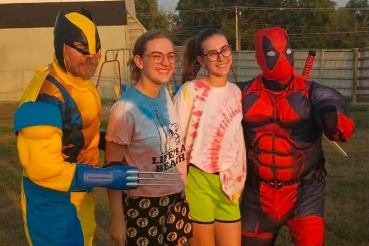 Girls posing with people dressed as movie characters (Wolverine and Deadpool)