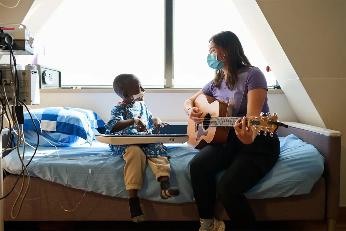 woman playing guitar and boy playing keyboard in hospital