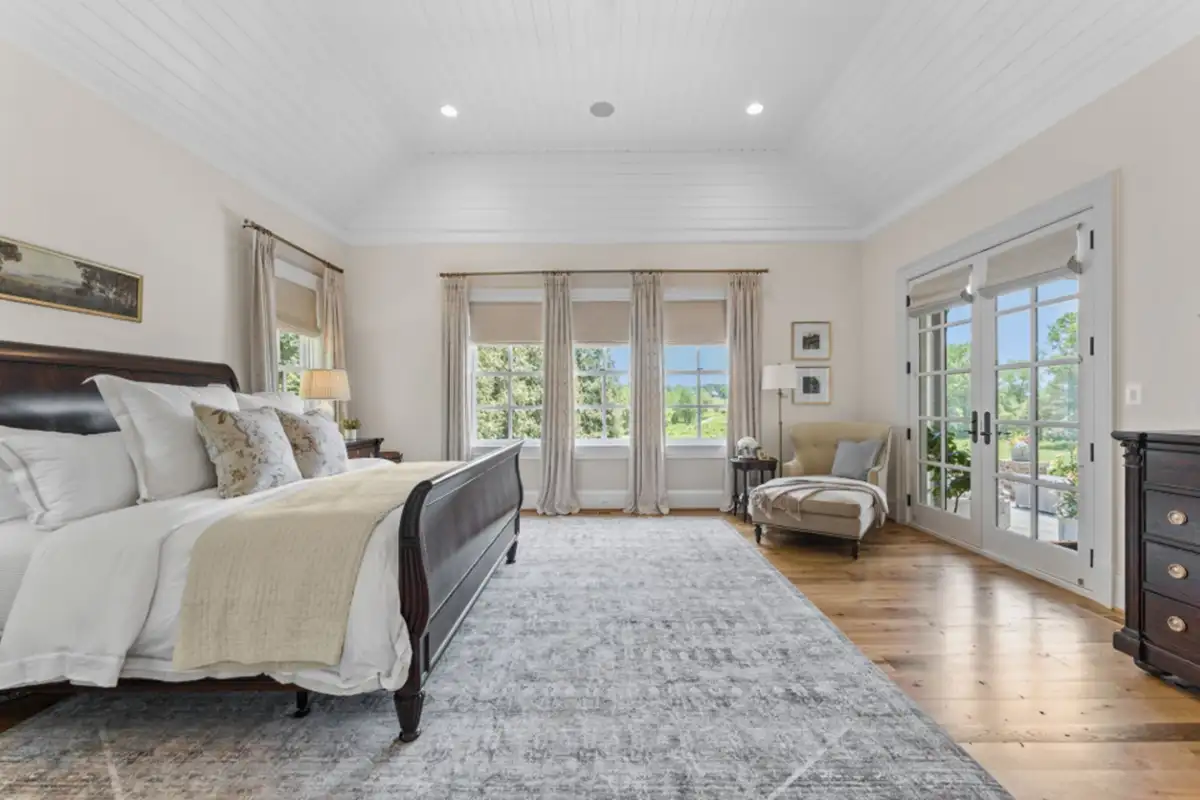 Primary bedroom with large windows, seating area, and access to patio of 22364 Wilson Meadows Ln