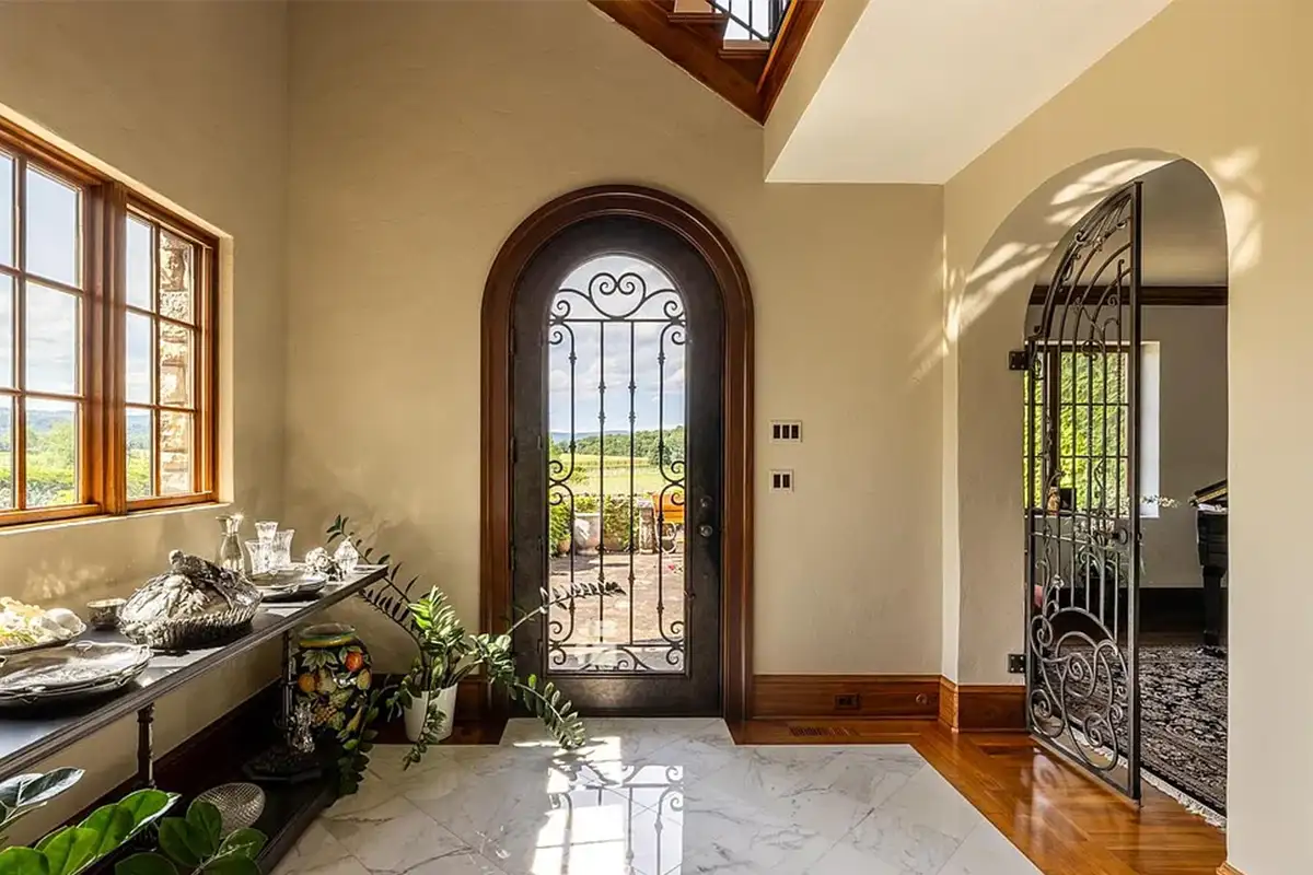 Foyer with wrought iron doors, marble tile and wooden flooring, and arched doorways of 2525 Gibson Ct