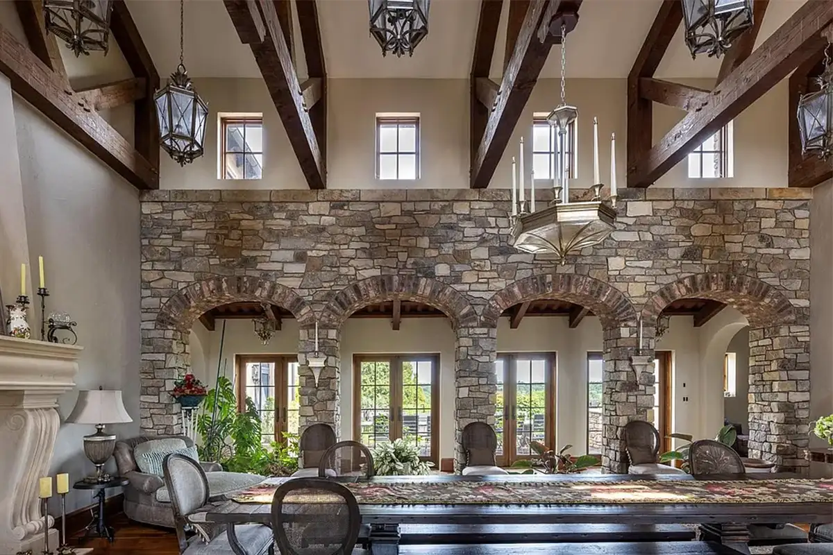 Grand formal dining room with stone walls, exposed wooden beams, gas fireplace, and wrought iron light fixtures of 2525 Gibson Ct
