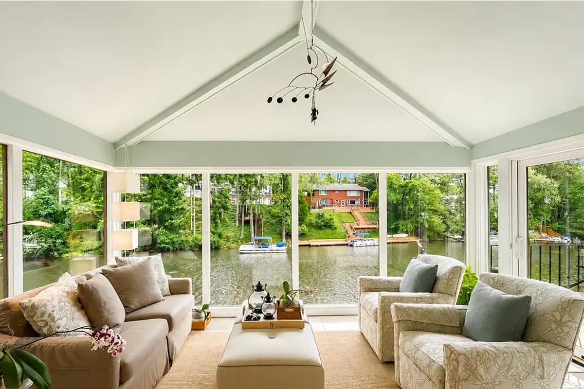 Sunroom with floor to ceiling windows, lakeside views, and tile flooring