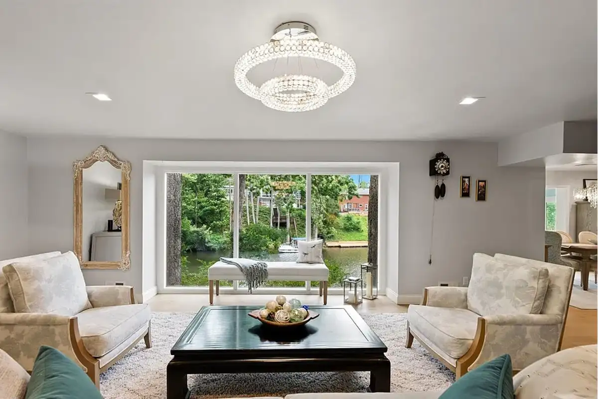 Living room with large windows, wood flooring, and crystal-like light fixtures