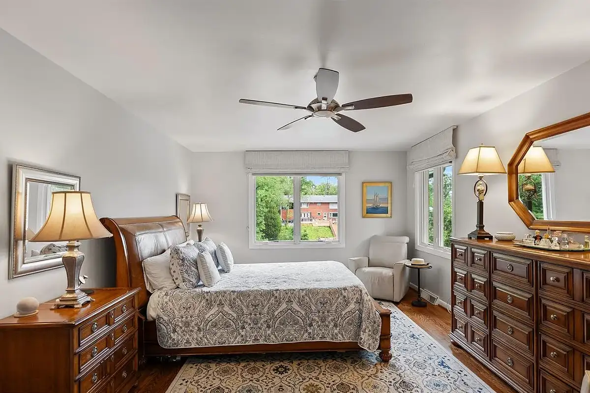 Primary bedroom with wood floors and two windows