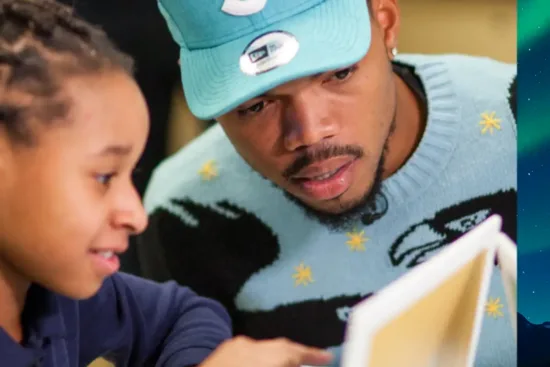Chance the Rapper looks at a laptop screen with a young child