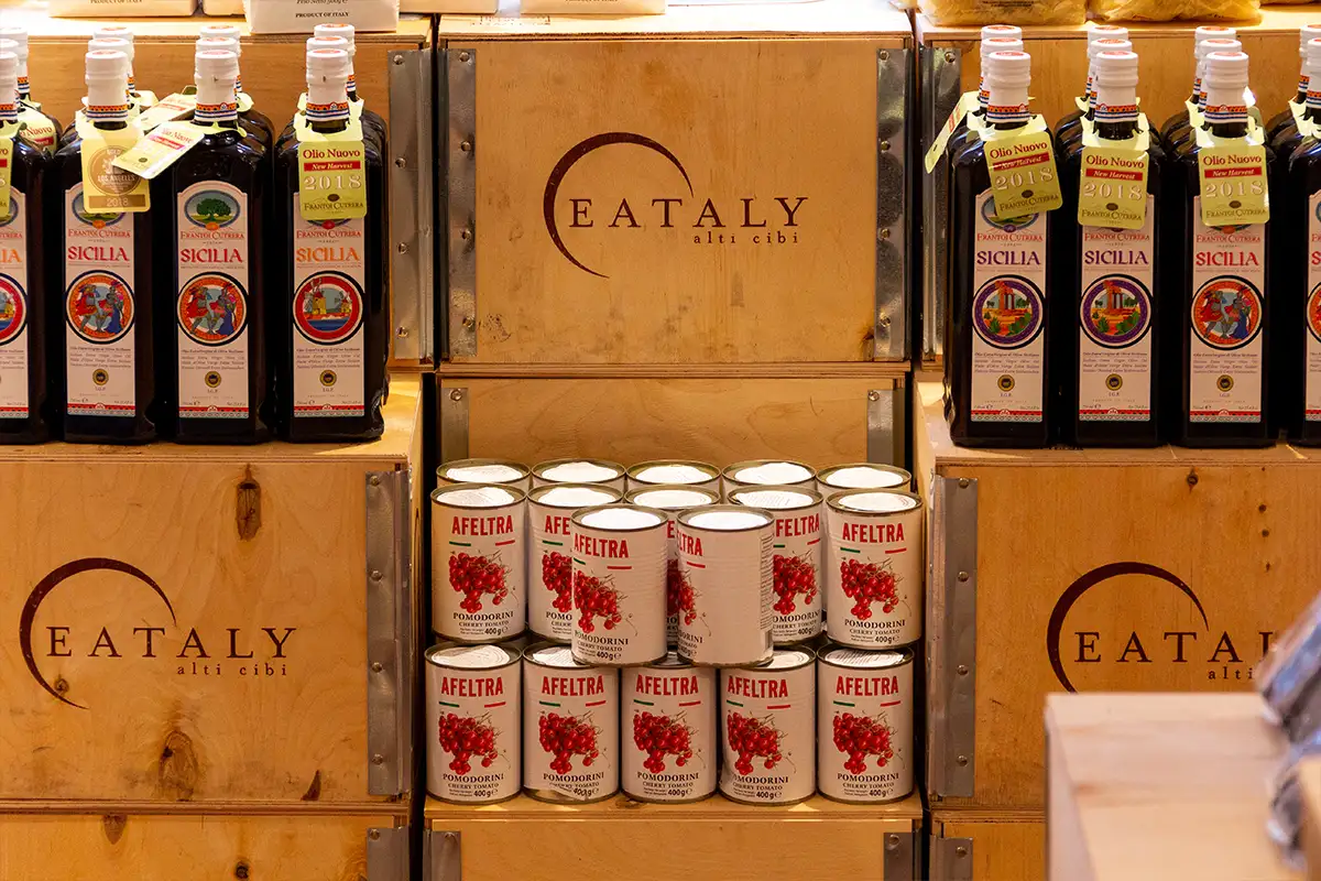 cans of tomatoes and olive oil arranged on crates with Eataly logos