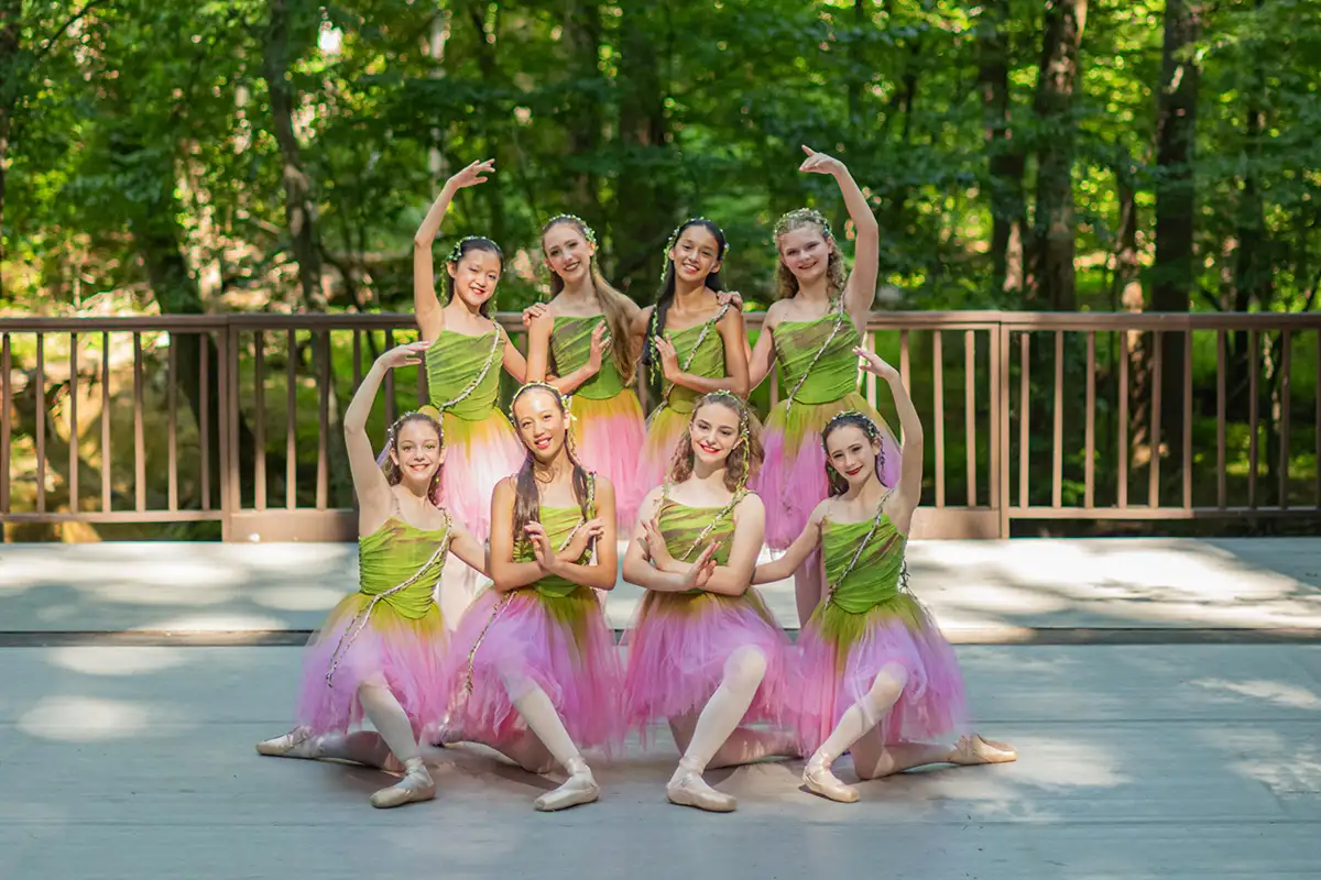 Ballerinas in green and pink tutus posing outside