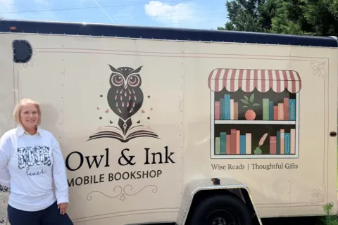 Stacie Malinowsk stands beside her Owl & Ink mobile bookshop