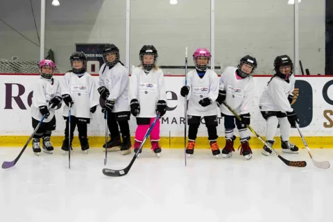 a group of girls on an ice rink in ice hockey gear