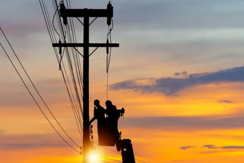 men in a bucket work on transmission power lines