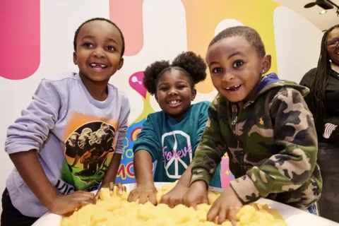 Three kids sticking hands in a tub of slime