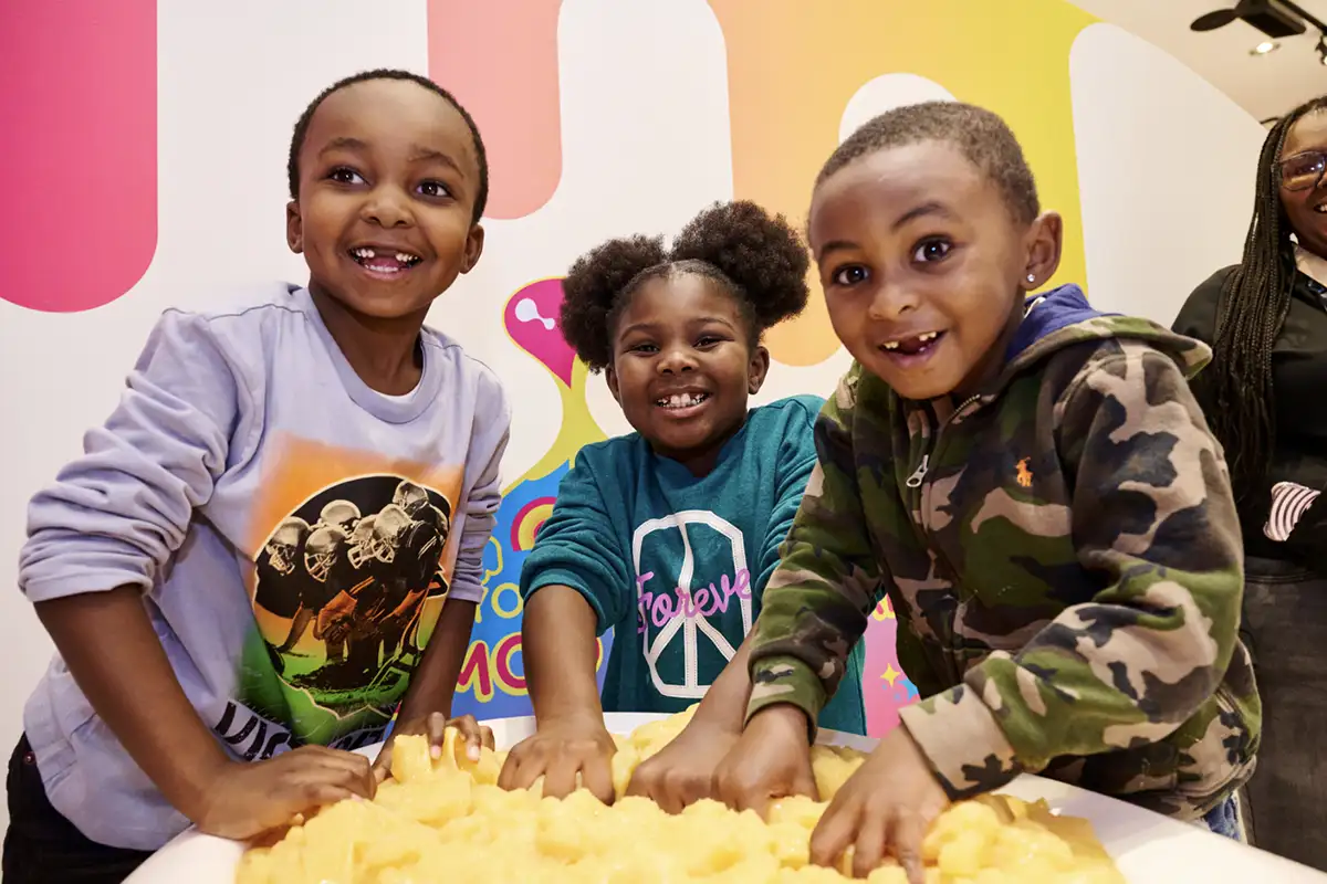 Three kids sticking hands in a tub of slime