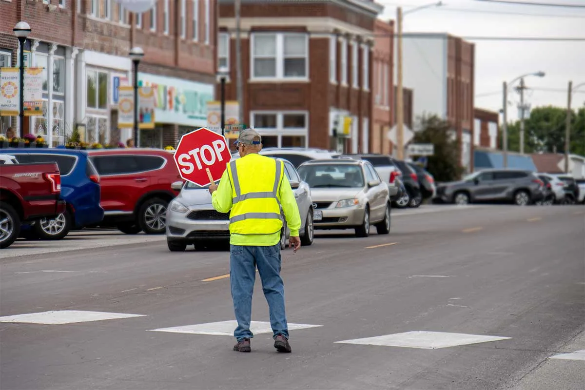 crossing guard with stop sign in traffic