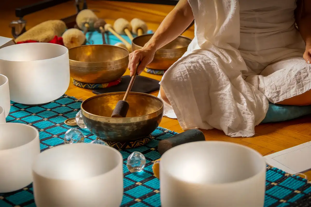 a person sits on the floor with sound bath bowls
