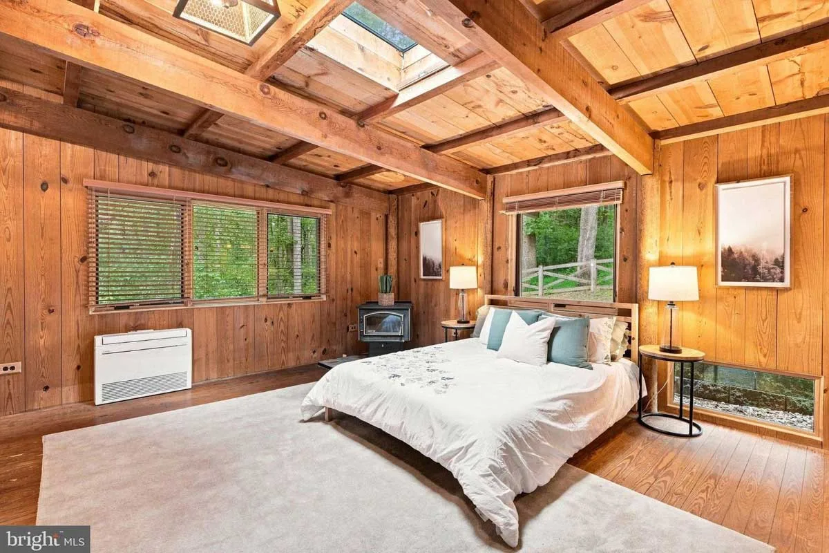 primary bedroom with skylights and windows surrounded by greenery