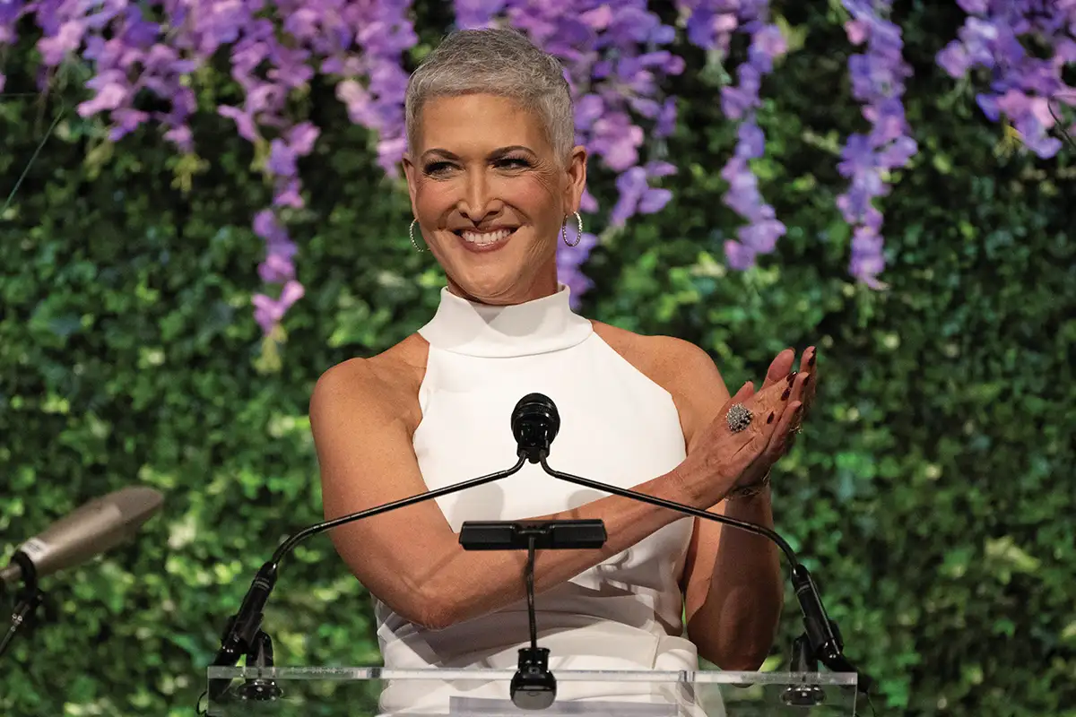 Jennifer Griffin speaking at podium with flowers in the background