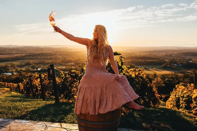 woman sitting on barrel holding a wine glass