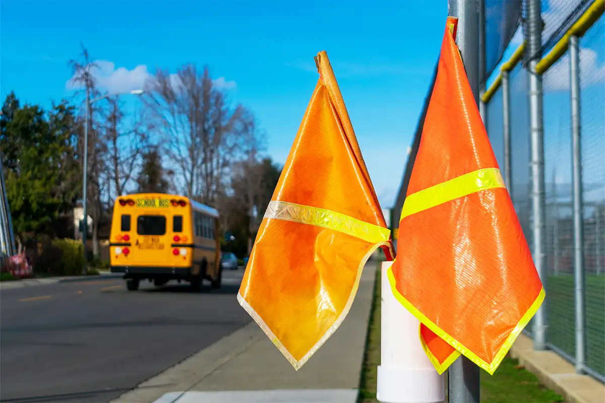 crossing guard flags with a school bus in the background