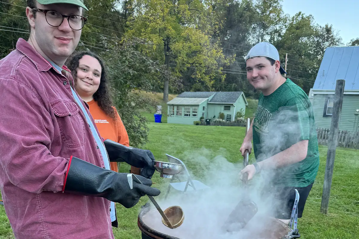people stir apple butter over a large crock at the Fall Fest at Catoctin Furnace