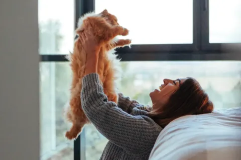Woman holding cat in the air