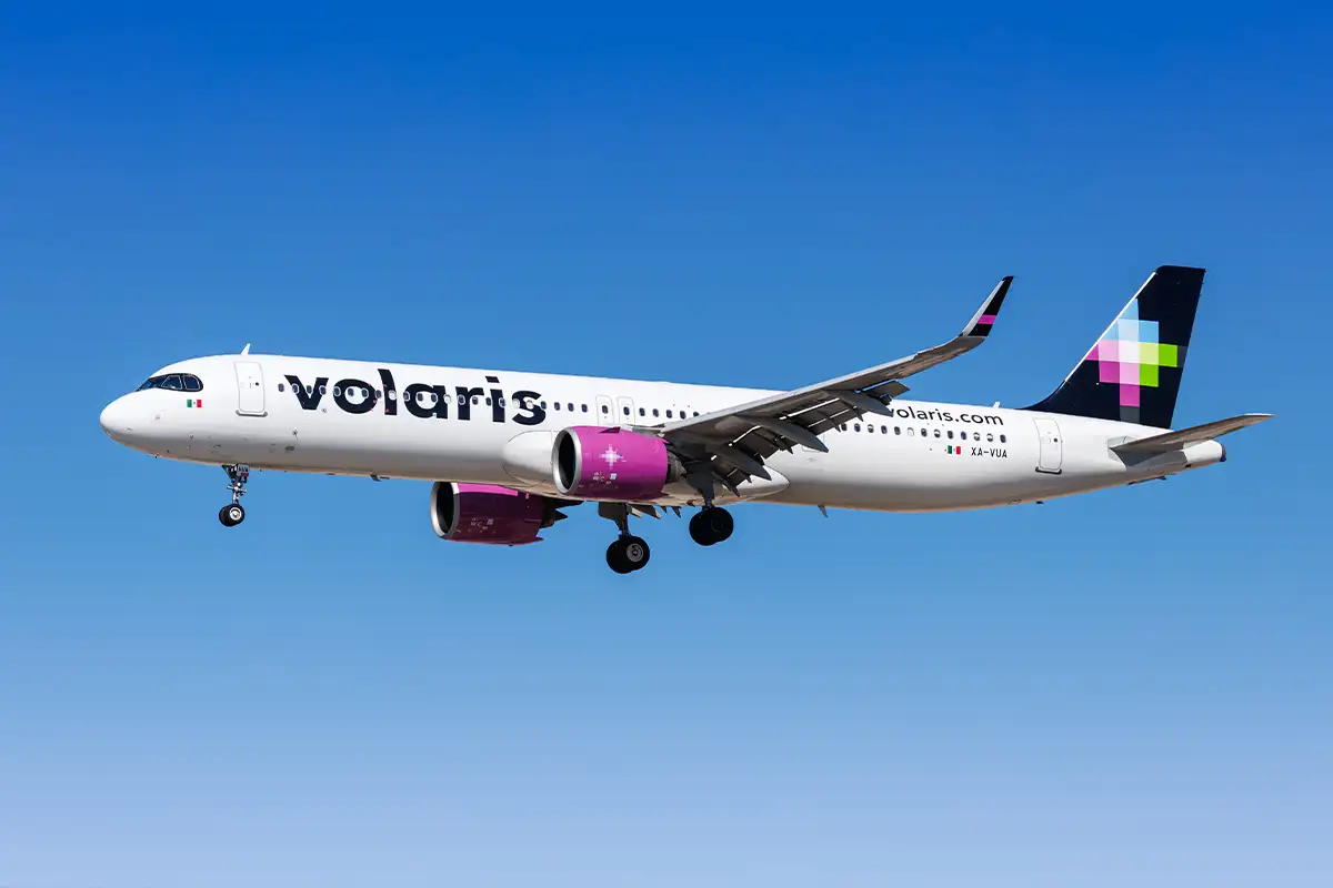 a Volaris airlines plane flying with a blue sky in the background