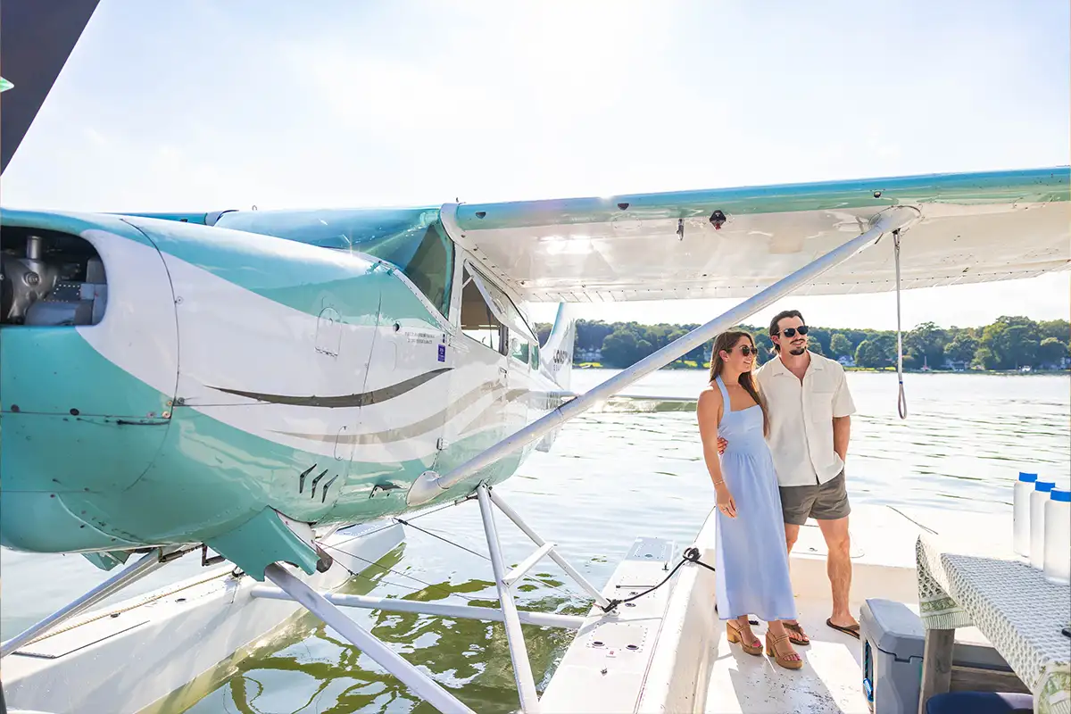 a man and woman stand on a dock next to a seaplane