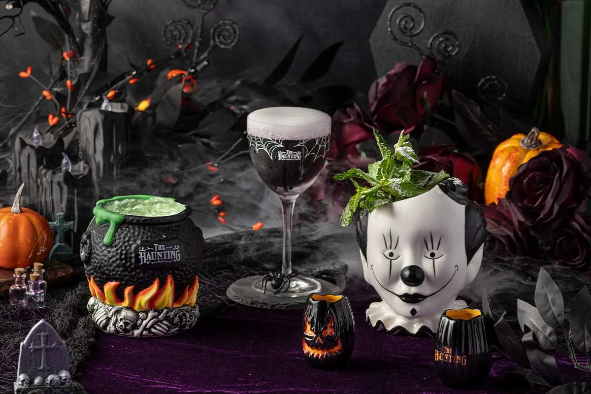 three cocktails in halloween-inspired glasses