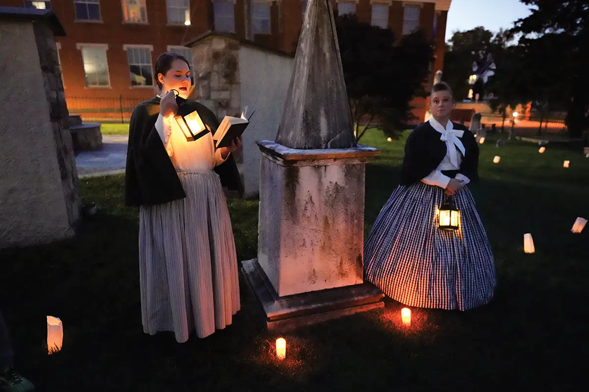 two women standing in graveyard with lanterns