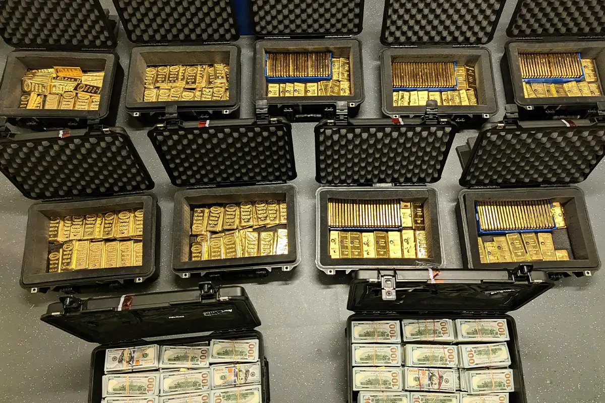 gold bars and stacks of cash lined up in bins on the floor