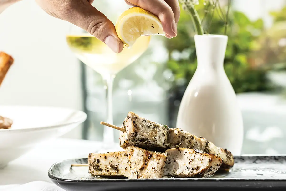 person squeezing fresh lemon over meat