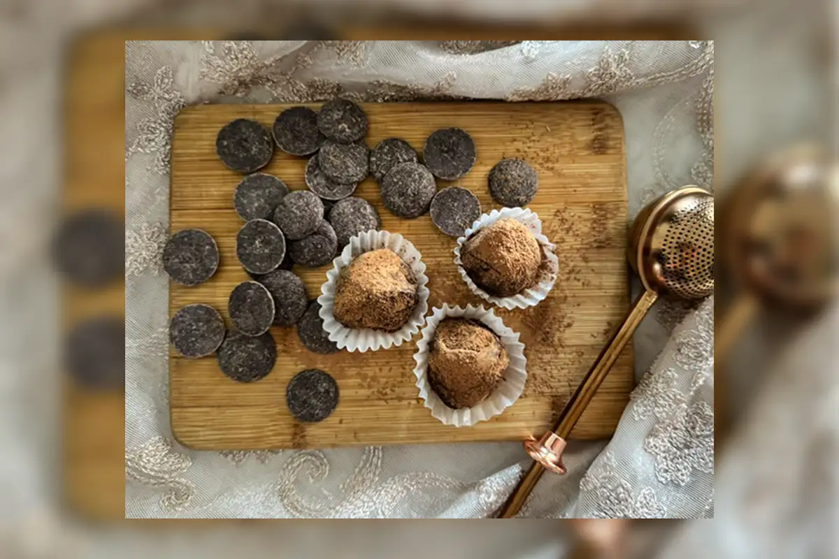 Small wooden cutting board with three chocolate truffles and dark chocolate circles on top